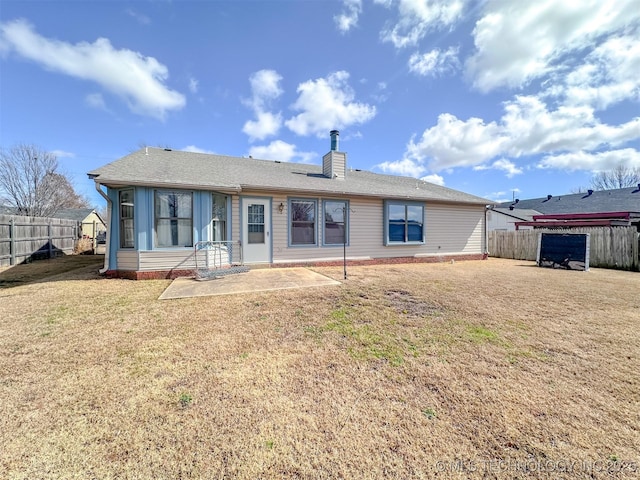 rear view of property with a yard, a chimney, a patio area, and fence