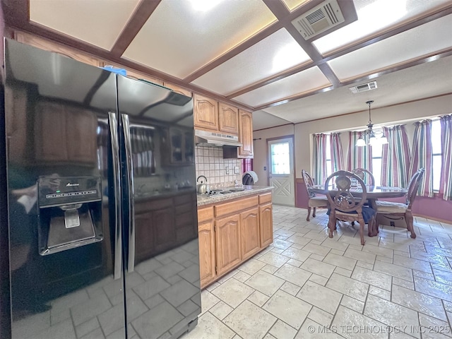 kitchen with light countertops, visible vents, black fridge with ice dispenser, and under cabinet range hood