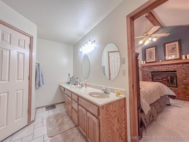 bathroom featuring a textured ceiling, a brick fireplace, a sink, and connected bathroom