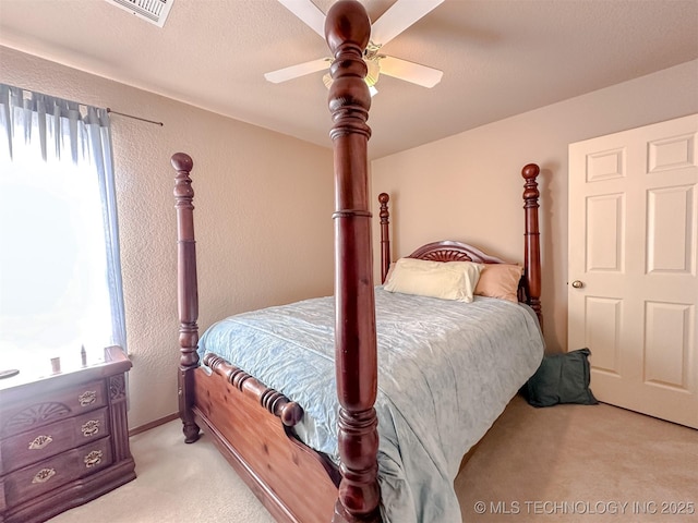 carpeted bedroom featuring multiple windows, visible vents, and a textured wall