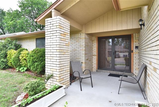 entrance to property featuring brick siding and a patio