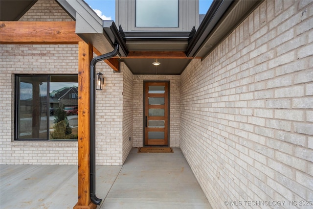 view of exterior entry featuring brick siding