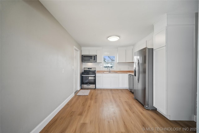 8301 E 133rd St S, Bixby, OK 74008 - kitchen with appliances with stainless steel finishes, light wood-type flooring, light countertops, baseboards, and white cabinets