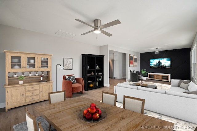 dining space featuring light wood-style floors, visible vents, an accent wall, and baseboards