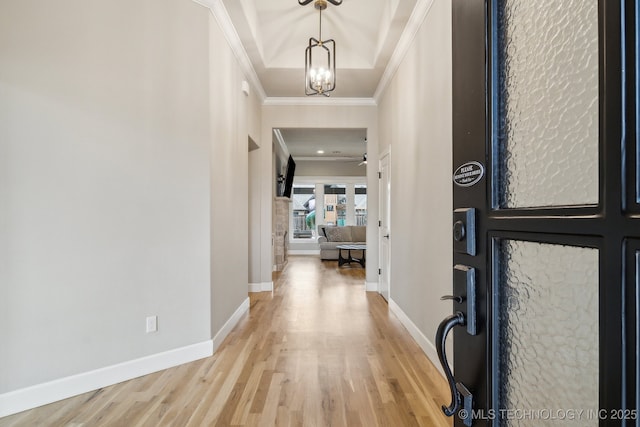 foyer featuring ceiling fan with notable chandelier, ornamental molding, light wood-type flooring, and baseboards