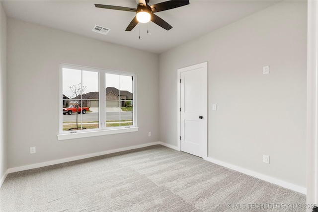 spare room with carpet floors, visible vents, a ceiling fan, and baseboards