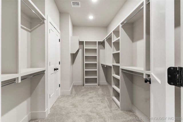 walk in closet with visible vents and light colored carpet