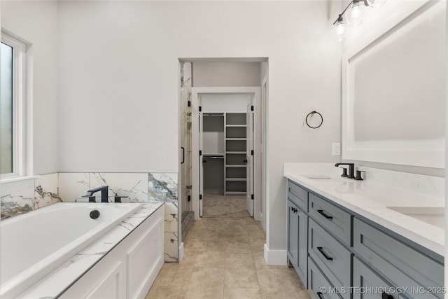 full bath featuring a bath, a sink, double vanity, a stall shower, and a walk in closet
