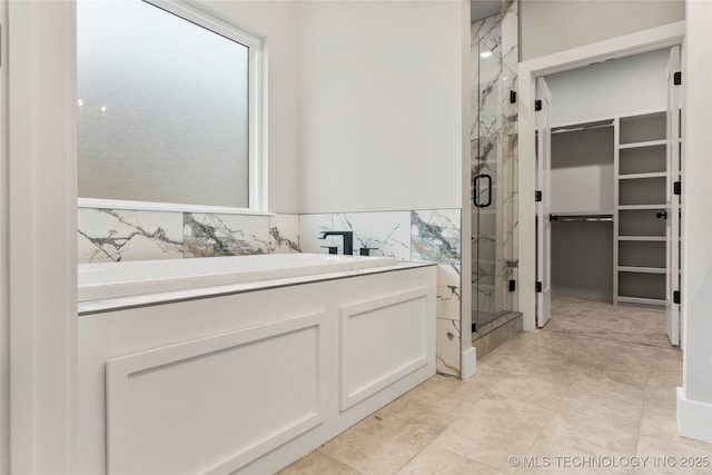 full bathroom with a walk in closet and a marble finish shower