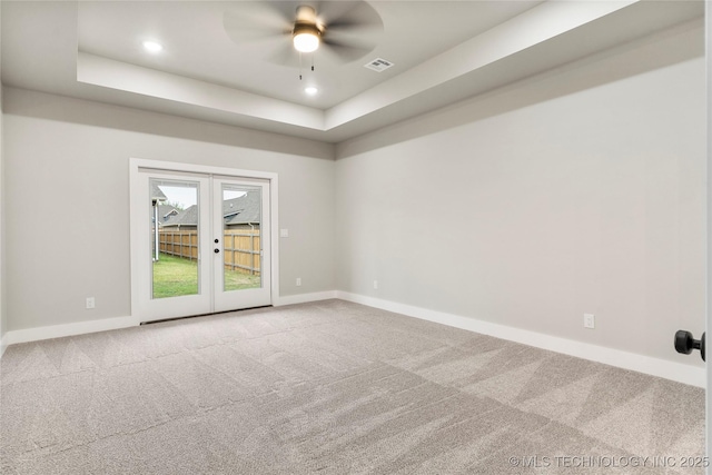 carpeted spare room with baseboards, a ceiling fan, visible vents, and a raised ceiling