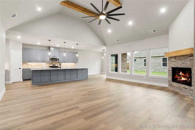 unfurnished living room with visible vents, high vaulted ceiling, and ceiling fan