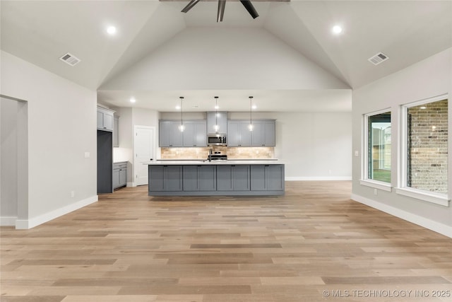kitchen with gray cabinets, decorative backsplash, appliances with stainless steel finishes, and visible vents