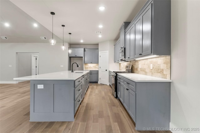 kitchen with light wood-style floors, appliances with stainless steel finishes, gray cabinets, and a sink