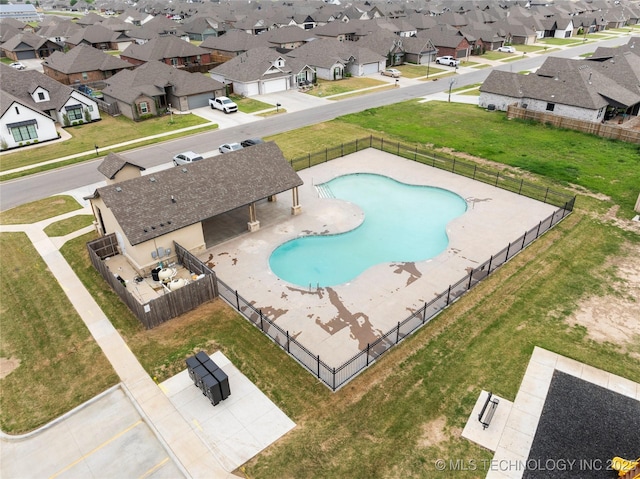 community pool featuring a residential view, a lawn, a patio, and fence