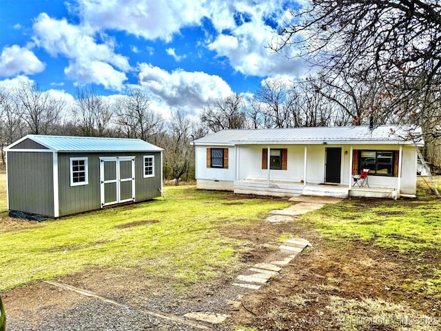 view of front facade featuring an outbuilding, metal roof, a storage shed, and a front lawn