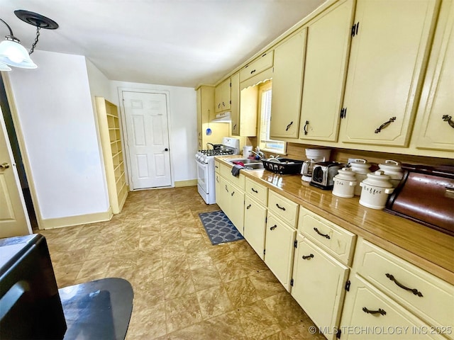 kitchen featuring cream cabinets, under cabinet range hood, baseboards, light countertops, and white gas range oven