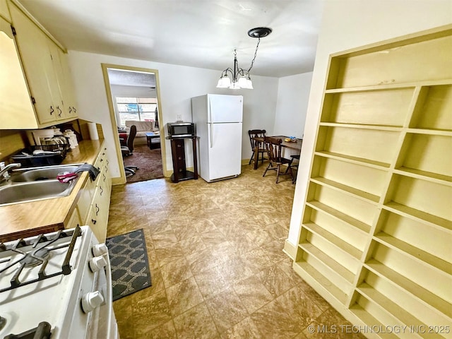 kitchen featuring white appliances, hanging light fixtures, light countertops, a chandelier, and a sink