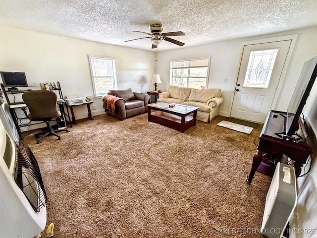 carpeted living room with plenty of natural light, baseboards, ceiling fan, and a textured ceiling