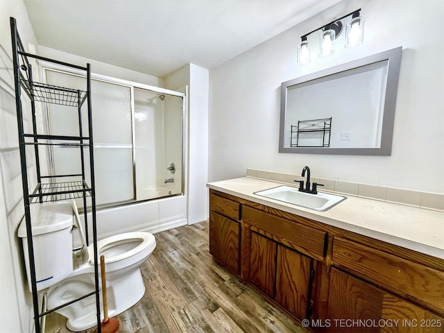 full bathroom featuring enclosed tub / shower combo, vanity, wood finished floors, and toilet