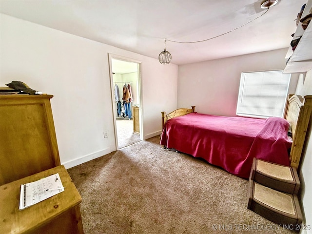 bedroom with a spacious closet, carpet flooring, and baseboards