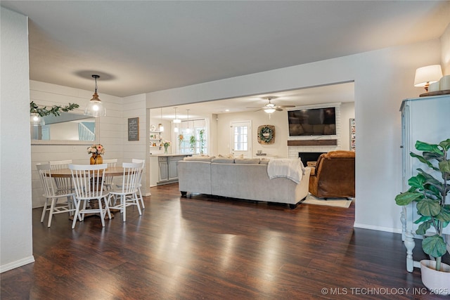 living room featuring dark wood-style floors, a fireplace, baseboards, and a ceiling fan