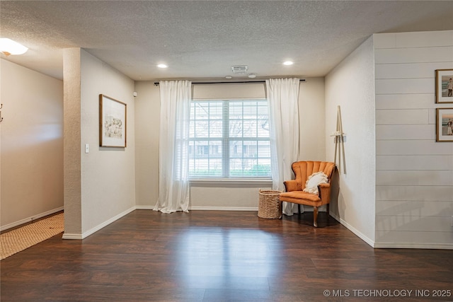 sitting room with visible vents, a textured ceiling, baseboards, and wood finished floors