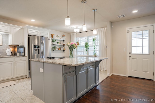 kitchen with tasteful backsplash, white cabinets, a center island, gray cabinets, and stainless steel refrigerator with ice dispenser