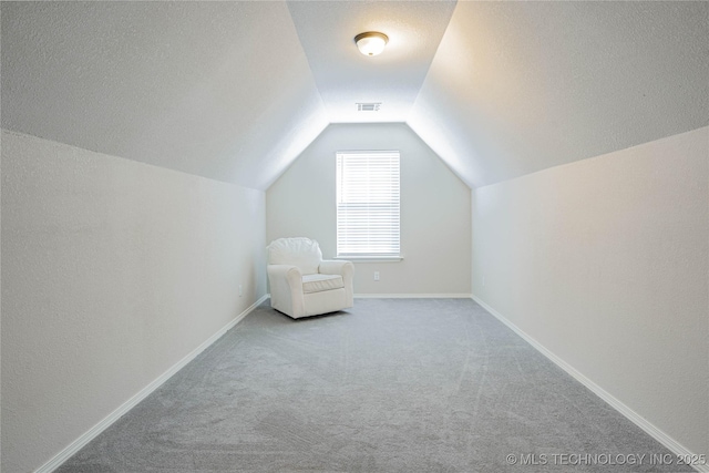 interior space with lofted ceiling, a textured ceiling, carpet flooring, visible vents, and baseboards