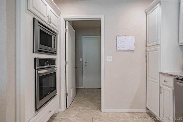 kitchen featuring stainless steel appliances, baseboards, white cabinets, and light stone counters