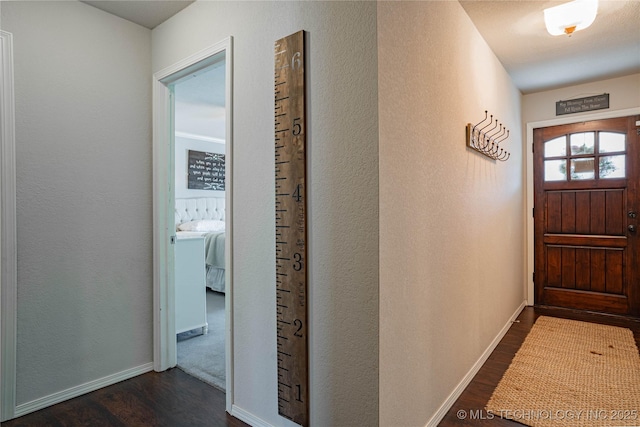 interior space with baseboards, dark wood-style flooring, and a textured wall