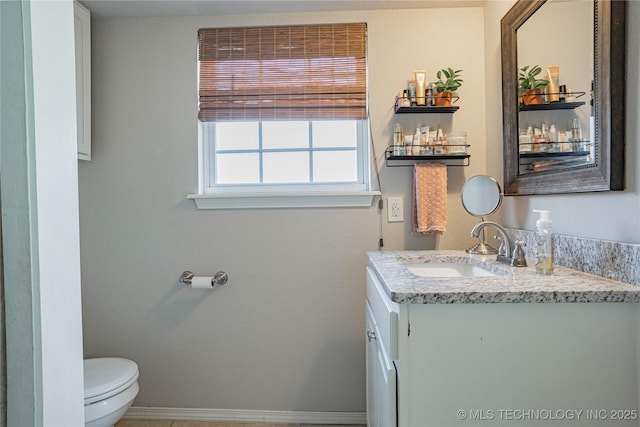 half bath featuring vanity, toilet, and baseboards