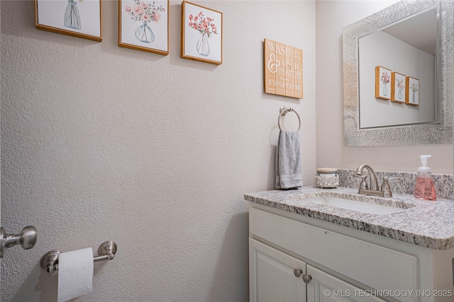 bathroom featuring a textured wall and vanity