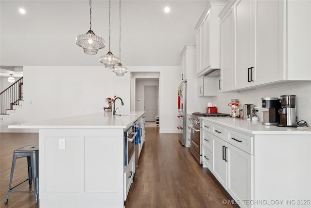 kitchen with high end appliances, light countertops, a sink, and a breakfast bar area