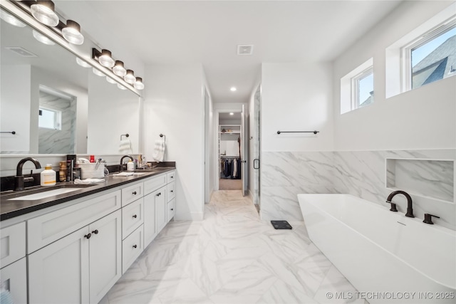 bathroom with a sink, visible vents, marble finish floor, a soaking tub, and double vanity