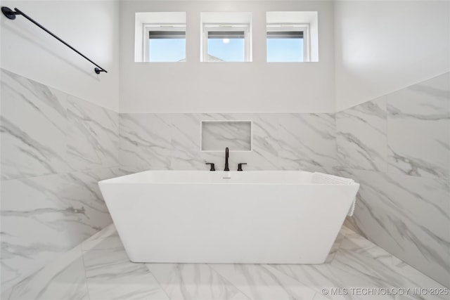 full bathroom featuring marble finish floor and a soaking tub