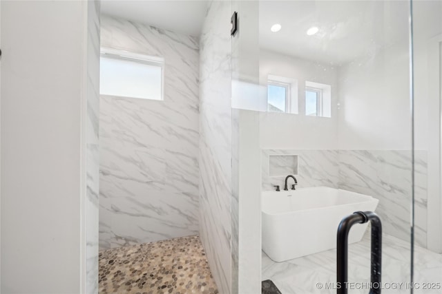 full bathroom featuring a healthy amount of sunlight, marble finish floor, a marble finish shower, and a freestanding tub