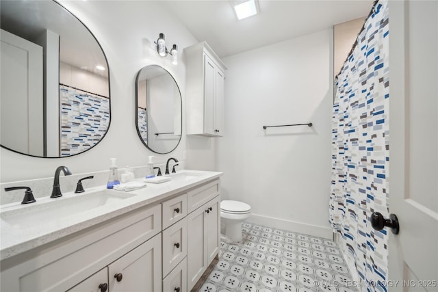 bathroom featuring double vanity, a sink, toilet, and baseboards