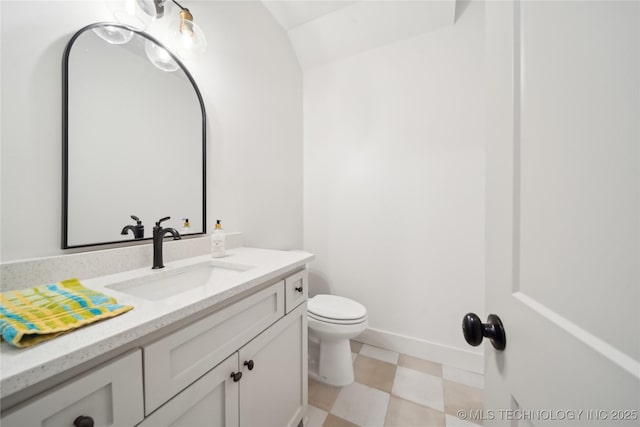 half bath featuring toilet, tile patterned floors, vanity, and baseboards