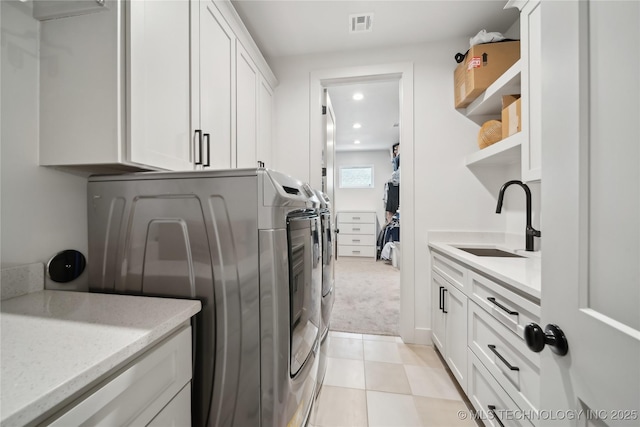 laundry room featuring washing machine and clothes dryer, light tile patterned floors, cabinet space, visible vents, and a sink