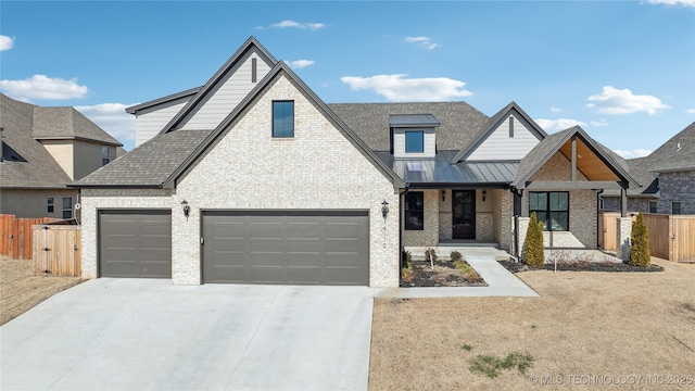 view of front of house featuring a standing seam roof, brick siding, fence, and concrete driveway