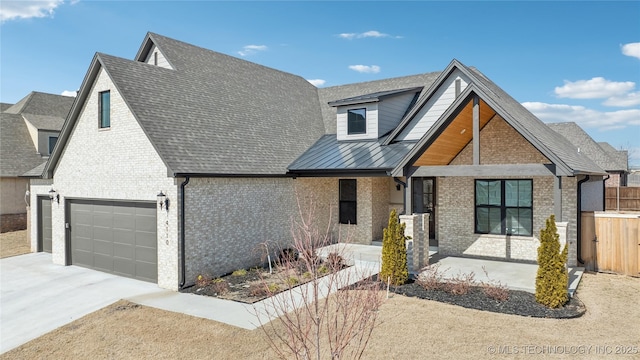 view of front of property with brick siding, concrete driveway, covered porch, metal roof, and a garage