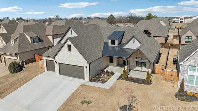 view of front of property featuring roof with shingles, concrete driveway, fence, metal roof, and a residential view