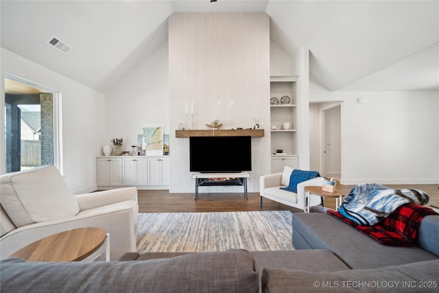 living area with built in features, baseboards, visible vents, wood finished floors, and high vaulted ceiling