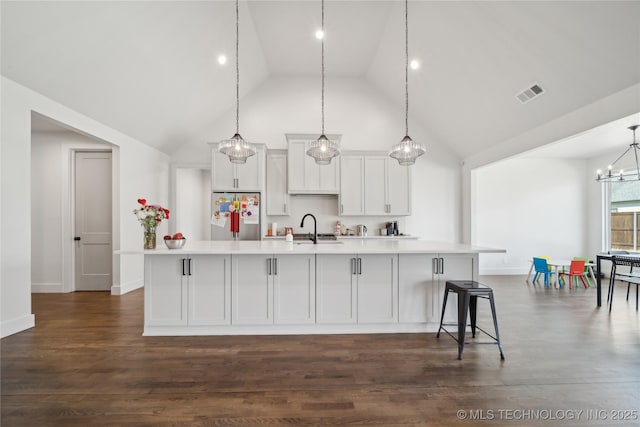 kitchen with visible vents, a spacious island, stainless steel refrigerator, light countertops, and a sink