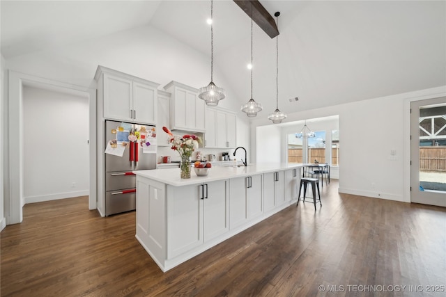 kitchen with dark wood-style floors, a large island with sink, high vaulted ceiling, and stainless steel refrigerator