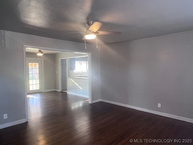 unfurnished room with ceiling fan, a textured ceiling, dark wood finished floors, and baseboards