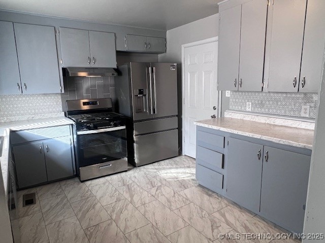 kitchen with under cabinet range hood, gray cabinets, appliances with stainless steel finishes, and marble finish floor