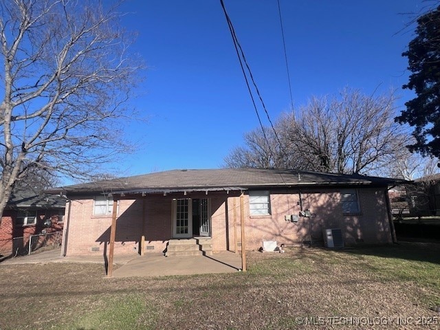 back of house with entry steps, brick siding, fence, a lawn, and a patio area