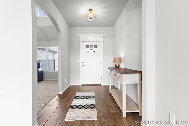 entrance foyer featuring arched walkways, wood finished floors, and baseboards