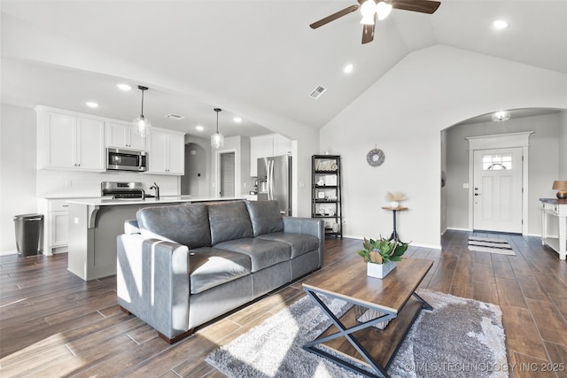 living area with arched walkways, visible vents, dark wood finished floors, and baseboards